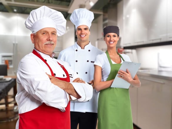 Three chefs posing in a kitchen