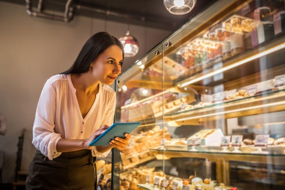 woman going through checklist in a bakery on a tablet