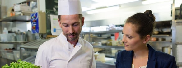 male chef speaking with female manager in a kitchen
