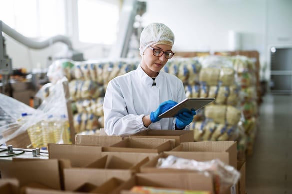 femlate worker using tablet to check boxes of packed food