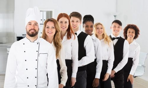 Resturant employees standing in a line behind a chef